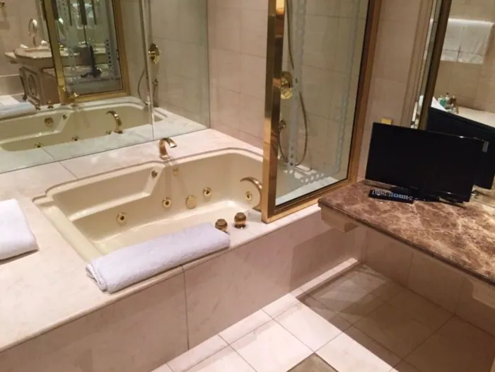 Bathroom with a marble-surround garden tub and mirrored wall.
