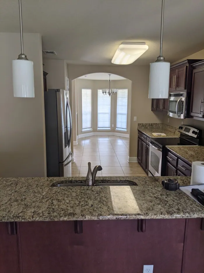 Kitchen with dark cabinetry, granite counters and pendant lighting over the sink.