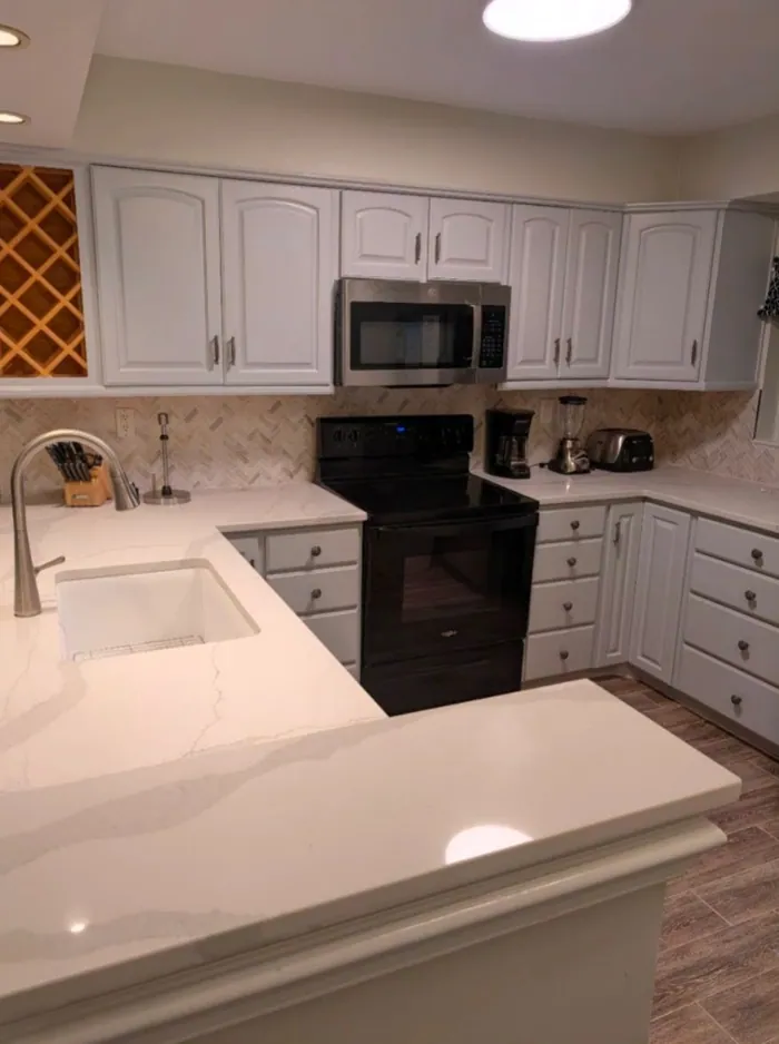 Kitchen with white cabinetry, quartz counters, tile backsplash and a wine lattice.
